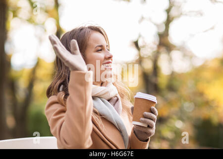 Felice giovane donna di bere il caffè in autunno park Foto Stock