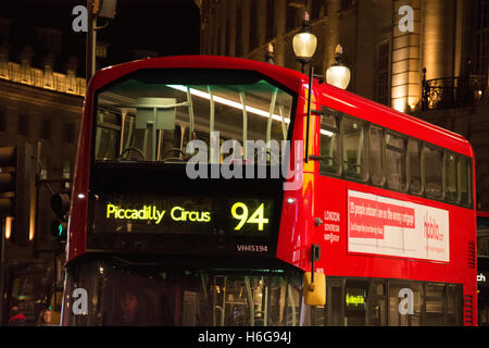 La notte gli autobus passano attraverso una illuminata luminosamente illuminata e Piccadilly Circus nel centro di Londra, Regno Unito Foto Stock