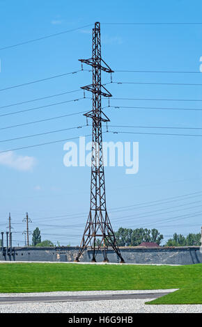 Alta tensione linea di tralicci energia elettrica con cavo contro lo sfondo della zona industriale Foto Stock