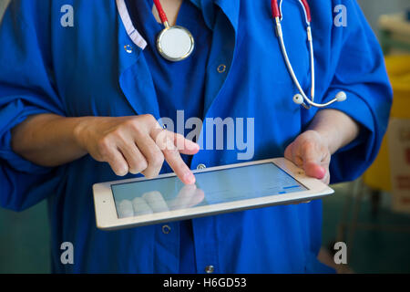 Un medico su una ward controlli a pazienti' registra su un Ipad Foto Stock