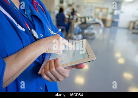 Un medico su una ward controlli a pazienti' registra su un Ipad Foto Stock