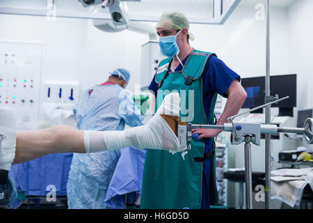 Un chirurgo e staff preparare il paziente per la chirurgia prima di effettuare una riduzione aperta e la fissazione interna di una caviglia sinistra Foto Stock