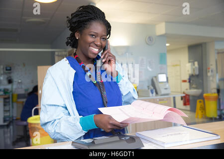 Un felice infermiera in un reparto in chat su un paziente sul telefono Foto Stock