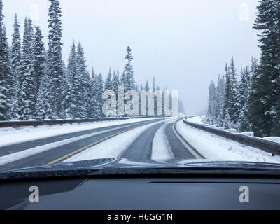 Conducente del punto di vista viewpoint guardando attraverso il parabrezza per auto vuoti di strada innevata in inverno la guida Foto Stock