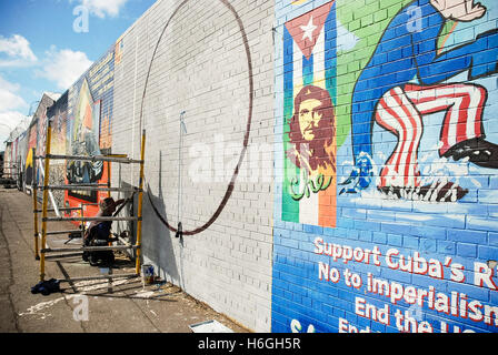 Artista Danny Devenney prepara una parete per un nuovo murale sulla pace internazionale a parete, Falls Road, Belfast. Foto Stock