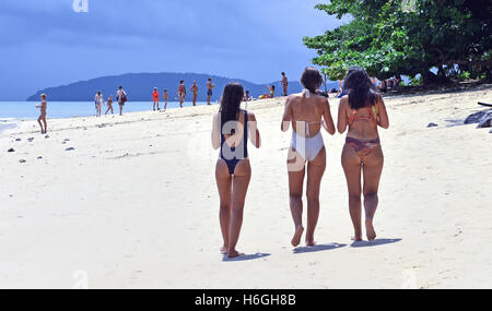 Tre donne in costume da bagno a piedi lungo la spiaggia di Railay in Thailandia. Foto Stock