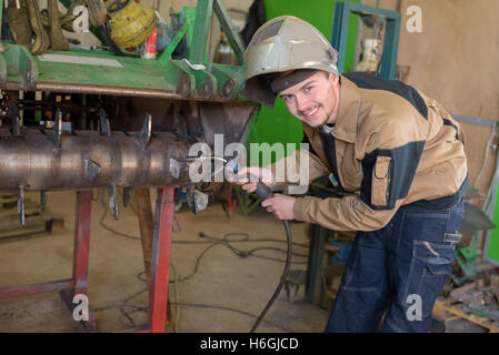 Felice apprendista saldatore a lavorare nell'impianto Foto Stock