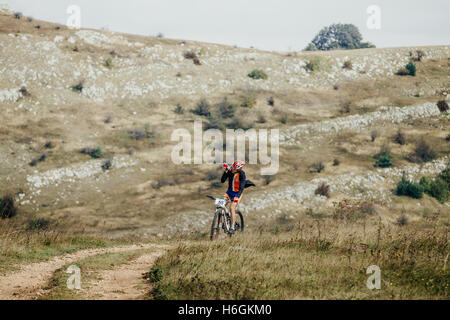 Racer ciclista in mountain bike di bere acqua da una bottiglia di Crimea durante la gara mountainbike Foto Stock