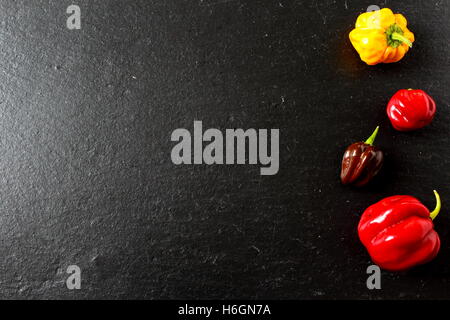 Composizione del coloratissimo peperoncino su una piastra di ardesia Foto Stock