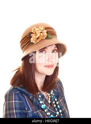 Un ritratto di una bella donna di mezza età in una camicia blu e collana con un cappello beige con fiori e capelli rossi per la Pentecoste Foto Stock