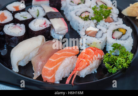 Varietà di sushi rotoli su un nero che serve il vassoio Foto Stock
