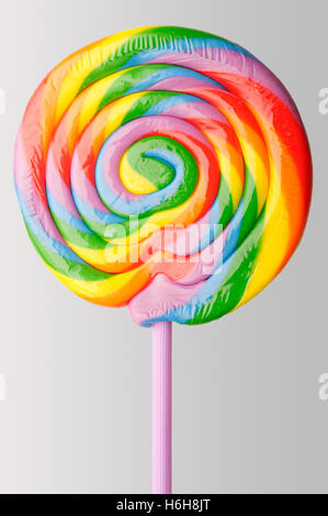 Round lollipop con colorati rainbow volute su uno sfondo semplice. Foto Stock