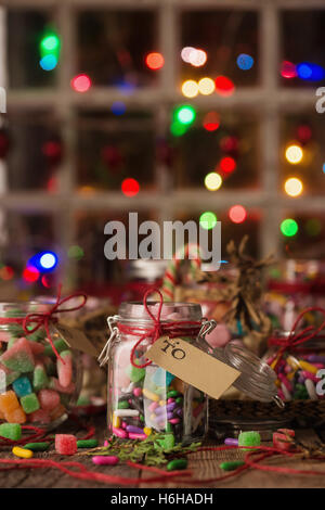 Varie caramelle in vasi per regali di Natale sulla tavola in legno rustico Foto Stock