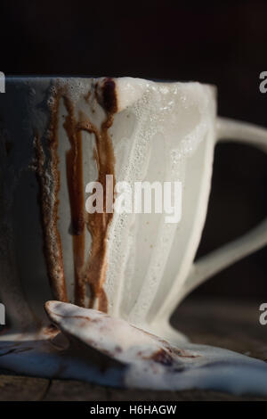 Molto disordinato di cioccolata calda con panna montata e salsa al cioccolato traboccante di una tazza alta impostata sul ceppo di albero Foto Stock