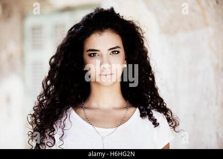 Bella giovane donna con ricci capelli neri all'aperto Foto Stock