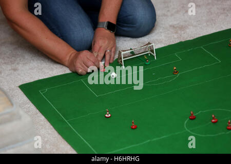 Un padre e suo figlio nella foto la riproduzione del Subbuteo® partita di calcio nella loro lounge a casa a Leeds, West Yorkshire, Regno Unito. Foto Stock