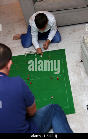 Un padre e suo figlio nella foto la riproduzione del Subbuteo® partita di calcio nella loro lounge a casa a Leeds, West Yorkshire, Regno Unito. Foto Stock