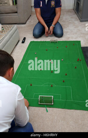 Un padre e suo figlio nella foto la riproduzione del Subbuteo® partita di calcio nella loro lounge a casa a Leeds, West Yorkshire, Regno Unito. Foto Stock