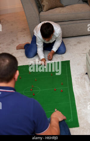 Un padre e suo figlio nella foto la riproduzione del Subbuteo® partita di calcio nella loro lounge a casa a Leeds, West Yorkshire, Regno Unito. Foto Stock