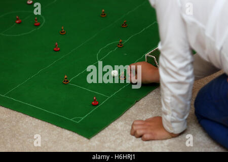 Un padre e suo figlio nella foto la riproduzione del Subbuteo® partita di calcio nella loro lounge a casa a Leeds, West Yorkshire, Regno Unito. Foto Stock