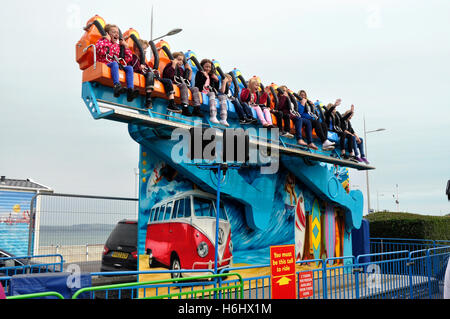 Fronte mare in fiera - bambini su un pauroso sky ride - facce eccitato - sventolando le mani - la luce del sole cielo blu - Weymouth Dorset Foto Stock