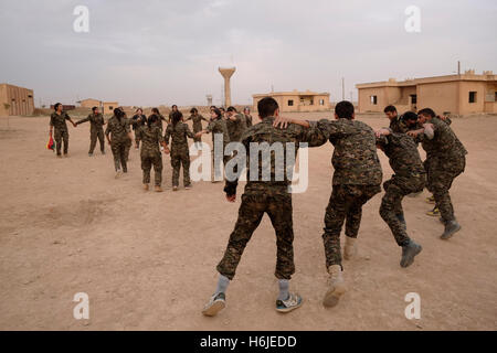 Combattenti curdi delle unità di protezione del popolo YPG e femmina Combattenti delle unità di protezione delle donne YPJ che eseguono un tradizionale Danza curda in un campo di allenamento in al Hasakah o. Distretto di Hassakeh nel nord della Siria Foto Stock