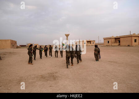 Combattenti curdi delle unità di protezione del popolo YPG e femmina Combattenti delle unità di protezione delle donne YPJ che eseguono un tradizionale Danza curda in un campo di allenamento in al Hasakah o. Distretto di Hassakeh nel nord della Siria Foto Stock