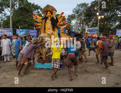 Durga Puja lavoratori spingere Durga idolo al fiume Gange per immersione a Babughat Kolkata, West Bengal, India. Foto Stock