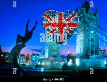 Turismo concettuale a tema divertente a forma di cuore frizzante riflettente Union Jack Flag motivo con il Tower Bridge e la statua di notte London REGNO UNITO Foto Stock
