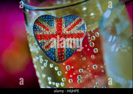 Concetto a forma di cuore frizzante riflettente Union Jack Flag motif con bicchieri di inglese vino spumante dietro Foto Stock