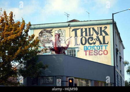 'Think local - boicottaggio Tesco' graffiti su un muro di una casa a Stokes Croft, Bristol, Inghilterra, Regno Unito Foto Stock