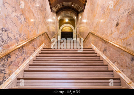 Una scala in marmo che conduce fino a porta con corrimano in oro in entrata della lobby per il Woolworth Building, New York, Foto Stock