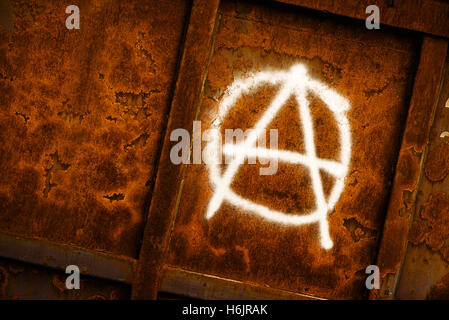 Anarchia simbolo graffiti verniciato a spruzzo su grunge corroso parete metallica Foto Stock