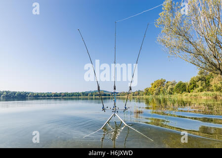 La pesca alla carpa ingranaggio (rod pod, bite allarmi, canne da pesca, mulinelli da pesca), sullo sfondo di un lago in una bella giornata di sole Foto Stock