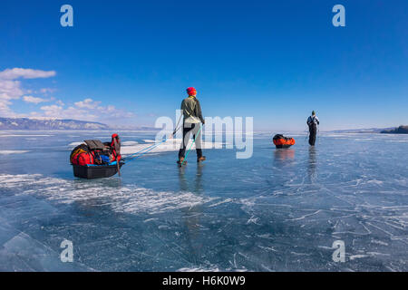 Una donna e un uomo con una mazza e trekking pole è sull'azzurro ghiaccio del Baikal Foto Stock