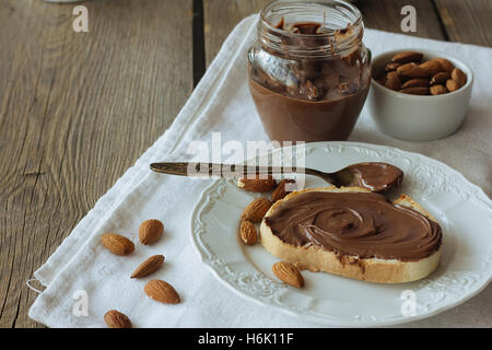 Pasta cioccolato sul pezzo di pane e mandorle spazio copia messa a fuoco selettiva Foto Stock