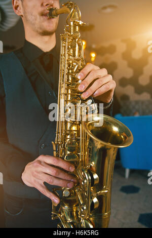 Giovane uomo in una tuta tenere il sassofono Foto Stock