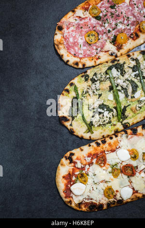 Tre tipi di pizza di ardesia scura con spazio di copia Foto Stock