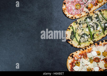 Tre tipi di pizza di ardesia scura con spazio di copia Foto Stock