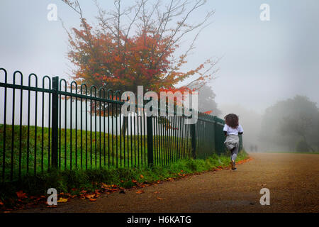 Una donna fa avanzare attraverso una nebbiosa Finsbiry Parco in autunno Foto Stock