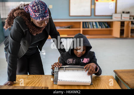 Un insegnante Ester Washinana aiuta i non vedenti allievo di utilizzare una macchina da scrivere braille durante la lezione di inglese a Eluwa scuola speciale in Ongwediva, Namibia Foto Stock