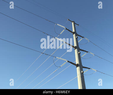 Metallo linea elettrica ad alta tensione contro un cielo blu sullo sfondo Foto Stock