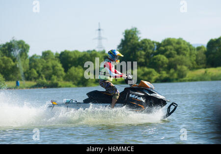 Uomo in motoslitta va veloce sull'acqua in estate Foto Stock