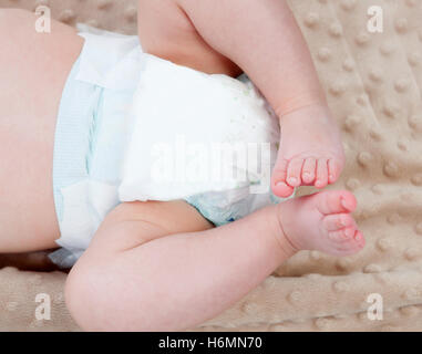 Le gambe di un bambino con il pannolino su una coperta Foto Stock