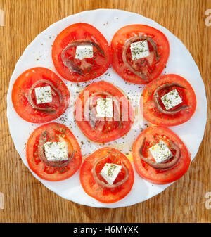 Gustose fette di pomodoro con formaggio e acciughe Foto Stock