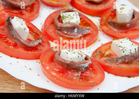 Gustose fette di pomodoro con formaggio e acciughe Foto Stock