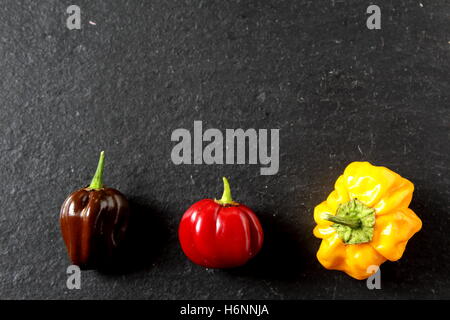 Composizione del coloratissimo peperoncino su una piastra di ardesia Foto Stock