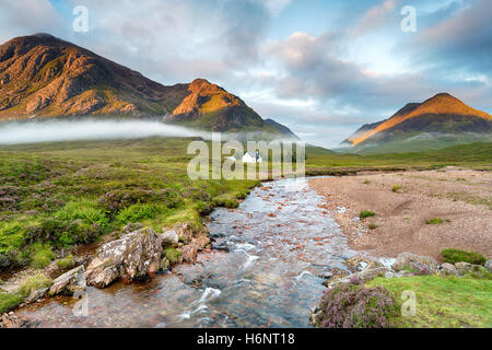 Il Rising Sun illuminazione i picchi di montagna a Glencoe nelle Highlands della Scozia Foto Stock