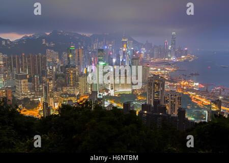 I grattacieli illuminati sull isola di Hong Kong in Hong Kong, Cina, visto dal Braemar Hill su una nebbia e nuvoloso sera. Foto Stock