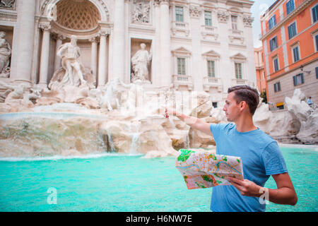 Uomo felice guardando citymap turistico vicino a Fontana di Trevi, Roma, Italia. Foto Stock